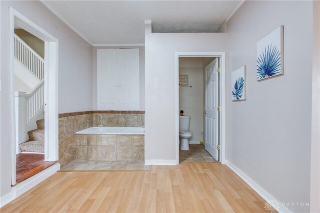 216 S Short St, Troy, OH 45373 - bathroom featuring wood finished floors, toilet, a garden tub, a textured ceiling, and baseboards