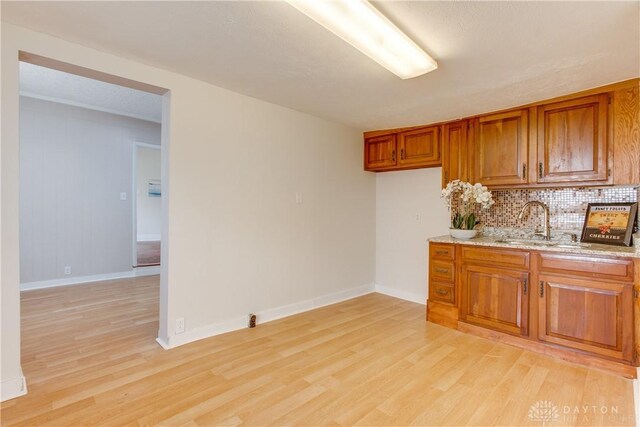 216 S Short St, Troy, OH 45373 - kitchen featuring brown cabinetry, light wood-style flooring, backsplash, light stone counters, and a sink