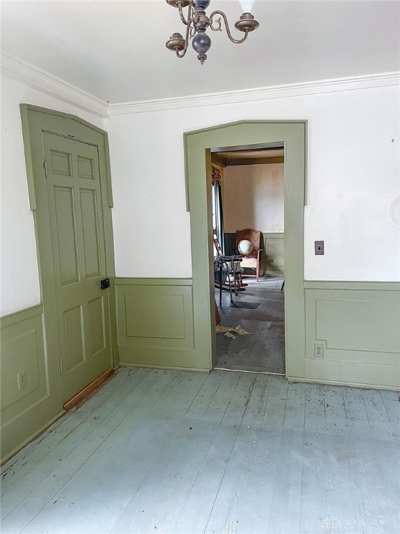 spare room featuring hardwood / wood-style flooring, an inviting chandelier, and crown molding