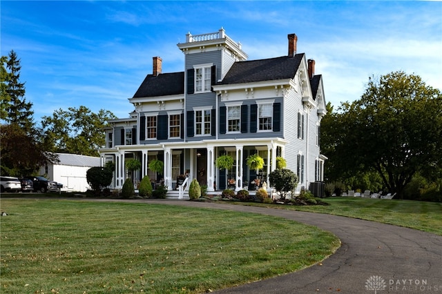 view of front of house with covered porch, a front yard, and central AC