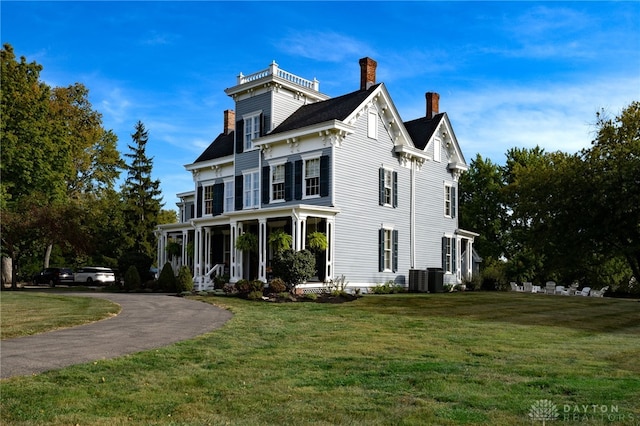 view of front of house with a front yard, central AC, and covered porch