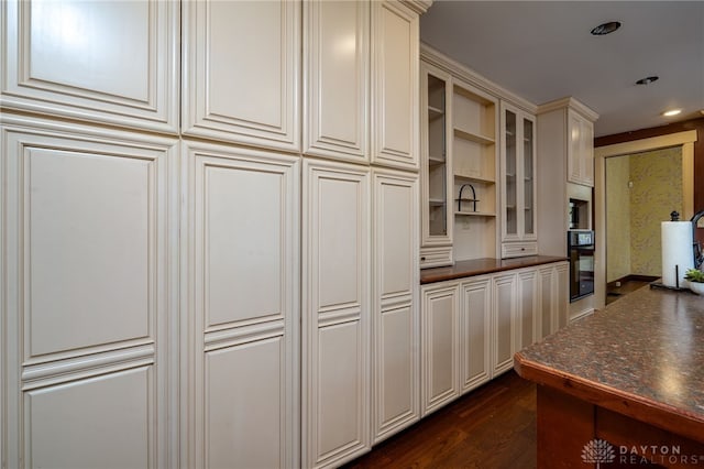 kitchen with cream cabinets, oven, and dark hardwood / wood-style floors