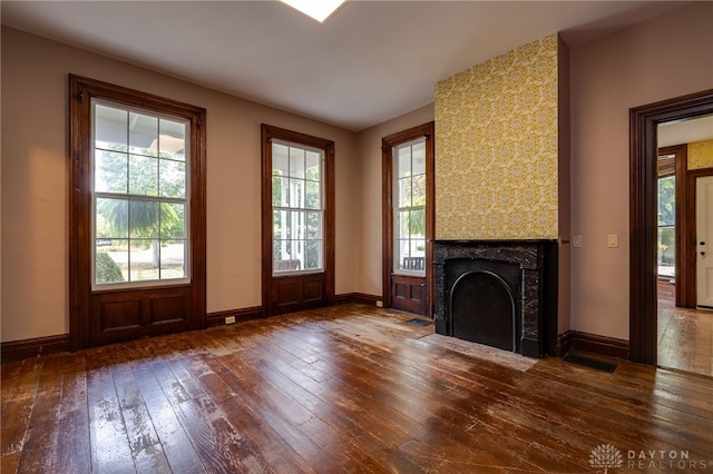 unfurnished living room with a fireplace, a wealth of natural light, and dark hardwood / wood-style floors