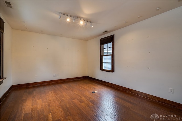 unfurnished room featuring track lighting and dark hardwood / wood-style floors