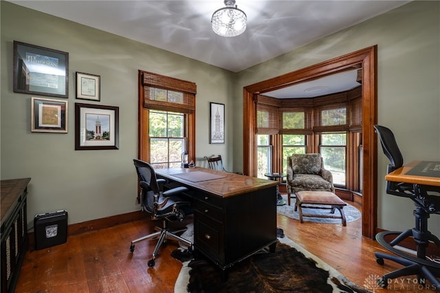 home office with a wealth of natural light and dark hardwood / wood-style floors