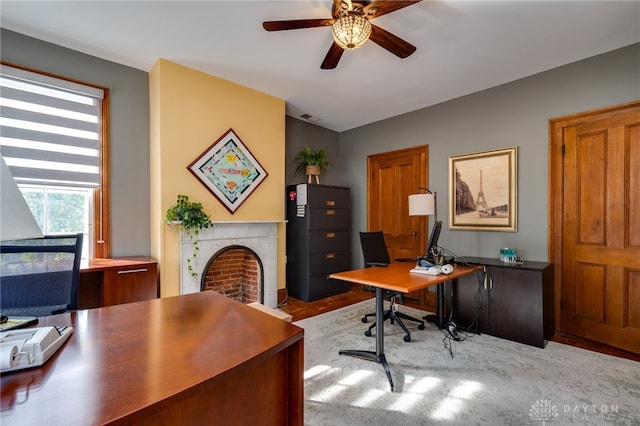 office with a fireplace, light hardwood / wood-style floors, and ceiling fan