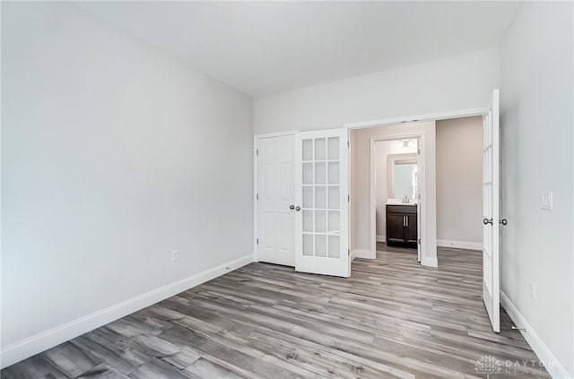 unfurnished bedroom with connected bathroom and hardwood / wood-style floors