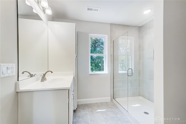 bathroom with tile patterned flooring, vanity, and walk in shower