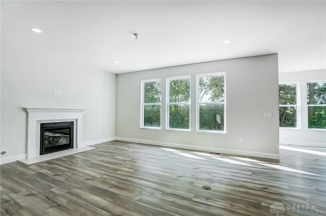 unfurnished living room featuring plenty of natural light and hardwood / wood-style floors