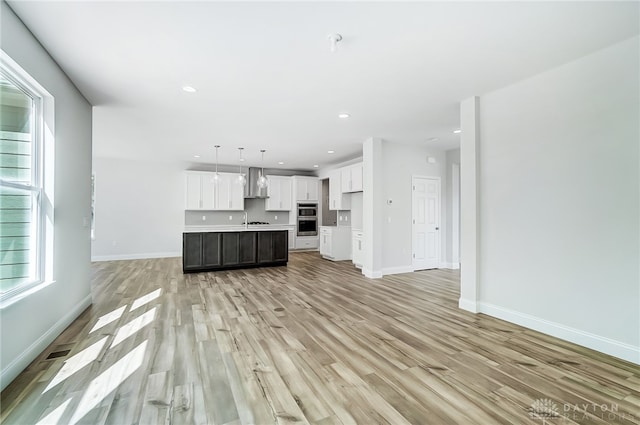 unfurnished living room featuring sink and light hardwood / wood-style floors