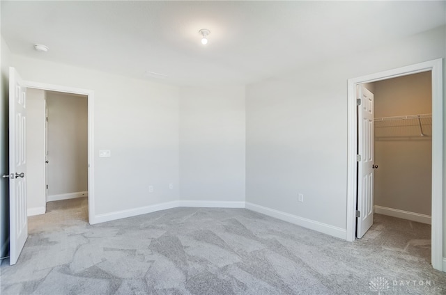 unfurnished bedroom with light carpet, a spacious closet, and a closet