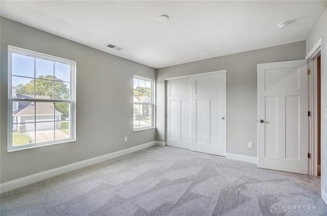 unfurnished bedroom with a closet, light carpet, and multiple windows