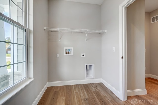 clothes washing area with light hardwood / wood-style floors, washer hookup, and hookup for an electric dryer