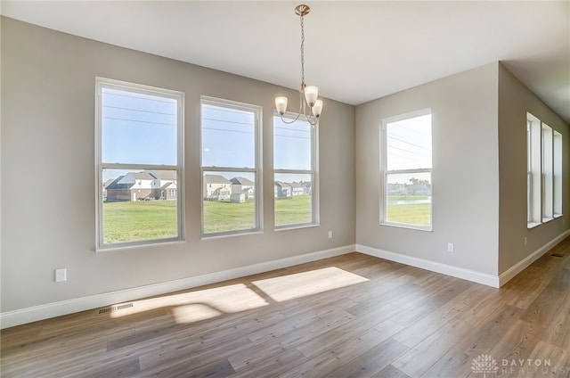 unfurnished dining area featuring a notable chandelier and hardwood / wood-style floors