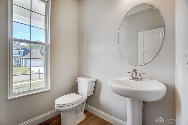 bathroom with plenty of natural light, toilet, and wood-type flooring