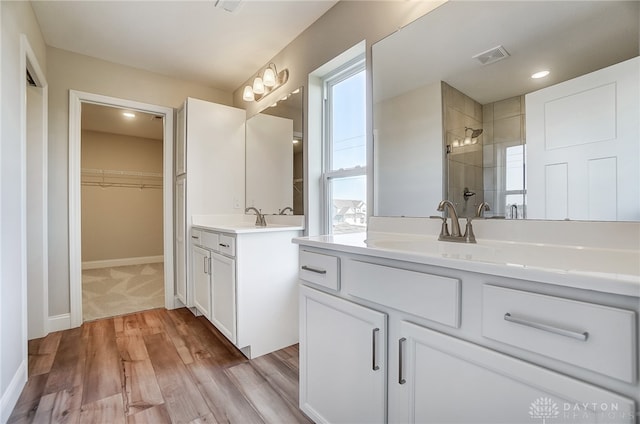 bathroom with vanity, hardwood / wood-style floors, and tiled shower