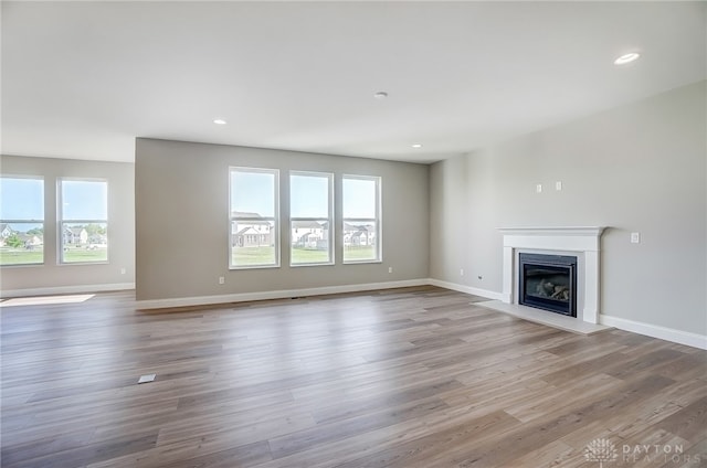 unfurnished living room featuring a wealth of natural light and hardwood / wood-style flooring