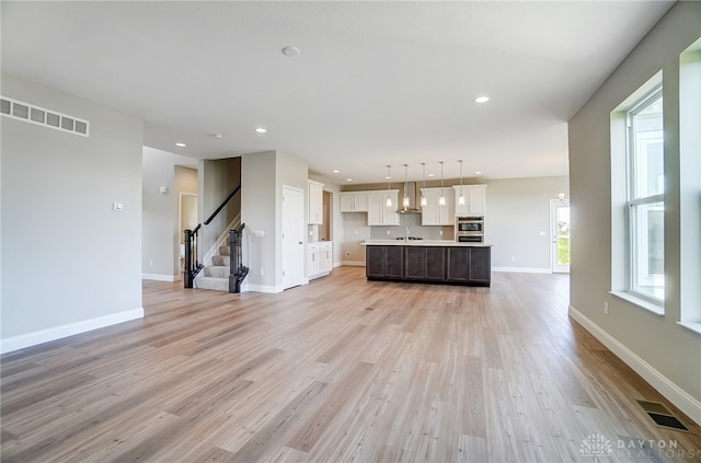 unfurnished living room featuring sink and light hardwood / wood-style floors