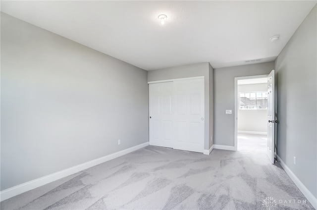 unfurnished bedroom with a closet and light carpet