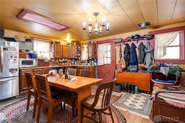 dining area with an inviting chandelier, wood ceiling, and light wood-type flooring