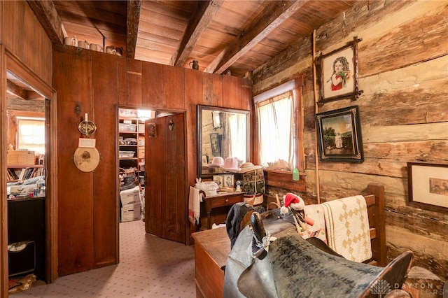 sitting room with plenty of natural light, light carpet, and wood walls