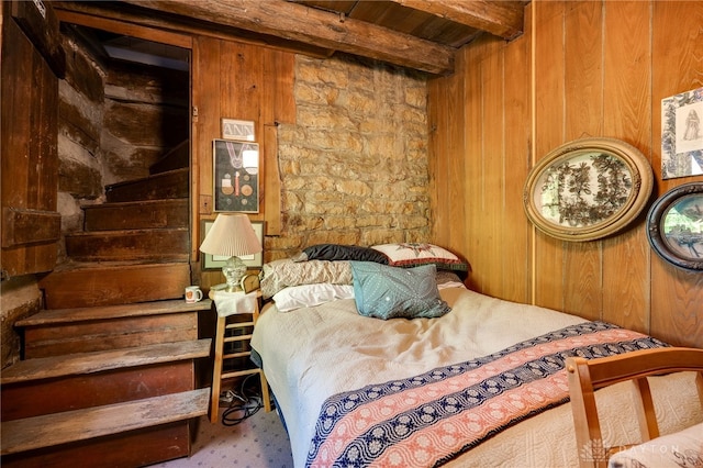 bedroom featuring wooden walls and beamed ceiling