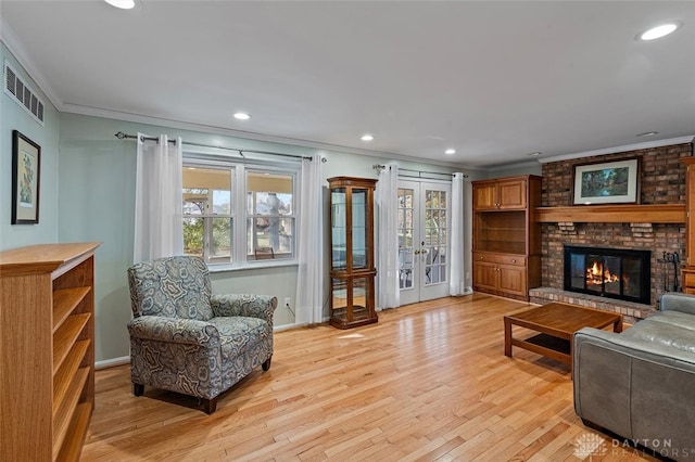 living room with a fireplace, french doors, brick wall, and light wood-type flooring