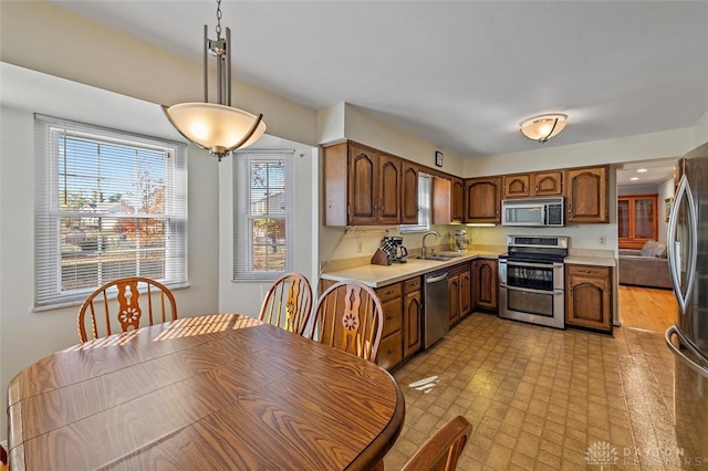 kitchen with light hardwood / wood-style floors, appliances with stainless steel finishes, pendant lighting, and sink