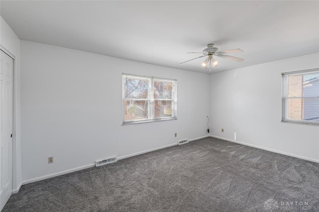 spare room featuring dark colored carpet and ceiling fan