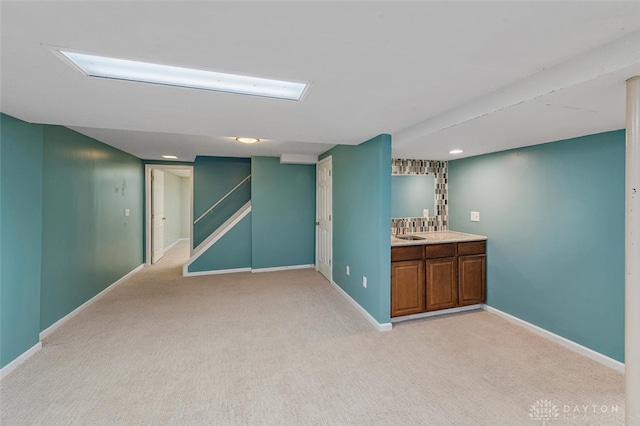 basement featuring light carpet and sink