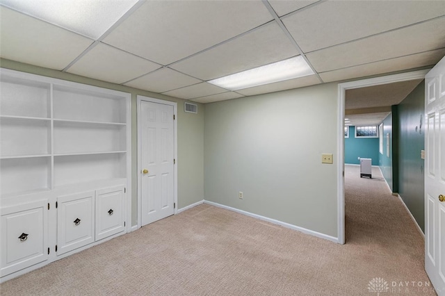 unfurnished room featuring light carpet and a drop ceiling