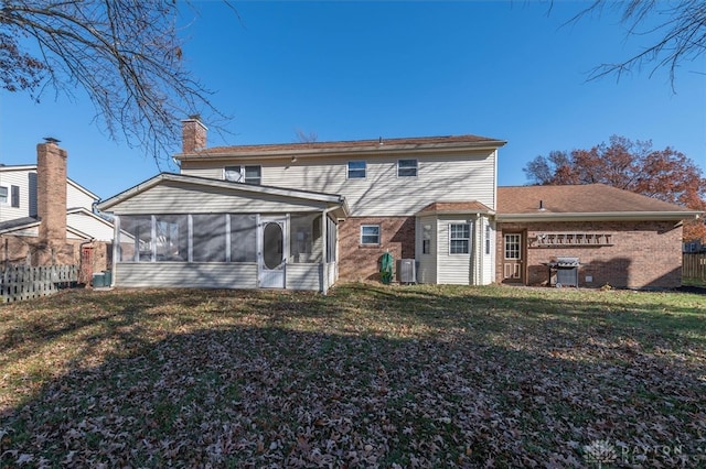 rear view of house with a yard, a sunroom, and central air condition unit