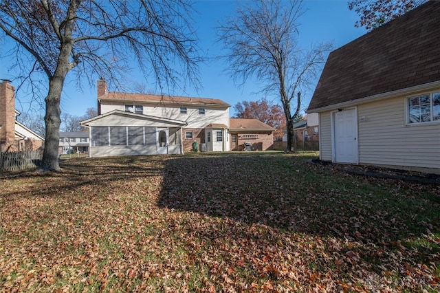 rear view of house with a sunroom and a lawn