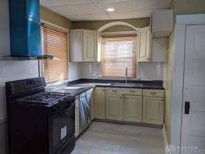 kitchen with tasteful backsplash, black range with gas stovetop, sink, cream cabinets, and range hood