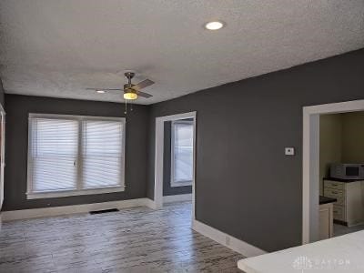 unfurnished room featuring hardwood / wood-style floors, a textured ceiling, and ceiling fan