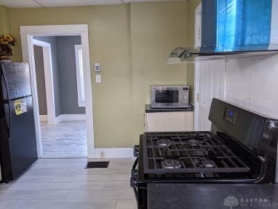 kitchen with light hardwood / wood-style flooring, black appliances, and range hood