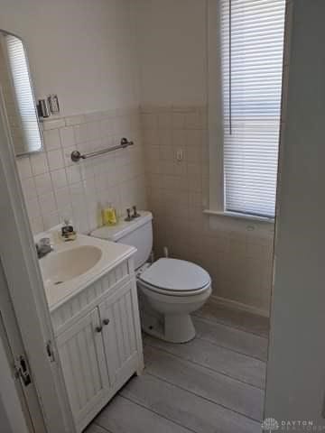 bathroom with vanity, tile walls, and toilet