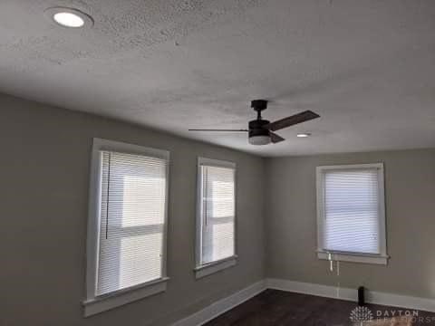 empty room with ceiling fan and a textured ceiling