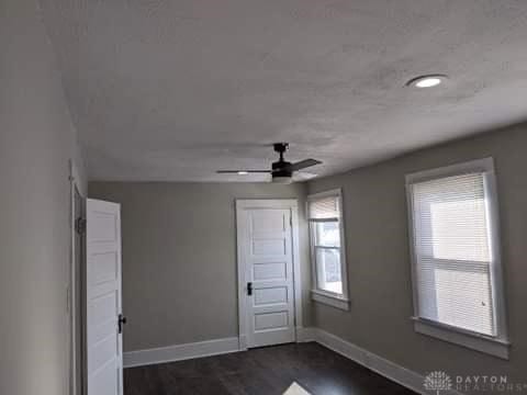 unfurnished room with dark hardwood / wood-style flooring and ceiling fan