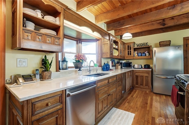 kitchen featuring beam ceiling, hanging light fixtures, light hardwood / wood-style flooring, sink, and stainless steel appliances