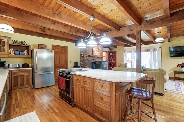 kitchen featuring a kitchen island, wood ceiling, pendant lighting, appliances with stainless steel finishes, and light hardwood / wood-style floors