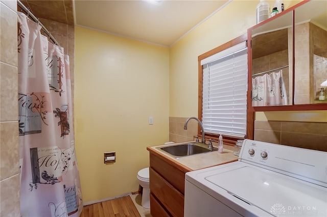 laundry area with washer / dryer, sink, crown molding, tile walls, and light hardwood / wood-style floors