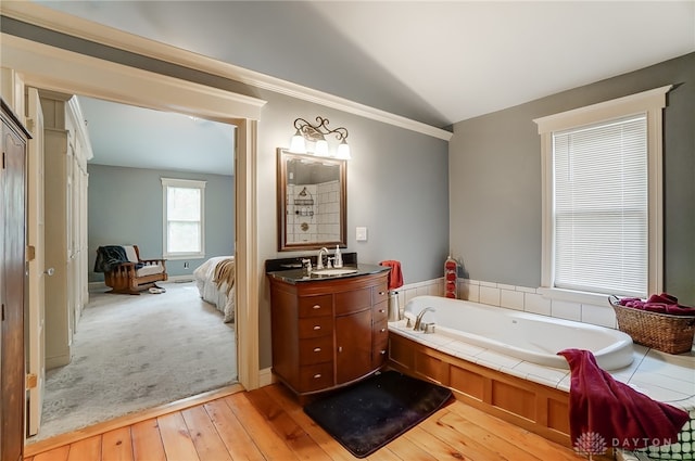 bathroom featuring vanity, a tub, vaulted ceiling, and hardwood / wood-style floors