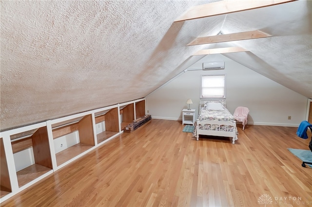 unfurnished bedroom featuring lofted ceiling, a textured ceiling, and light hardwood / wood-style flooring