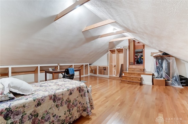 bedroom featuring a textured ceiling, wood-type flooring, and lofted ceiling