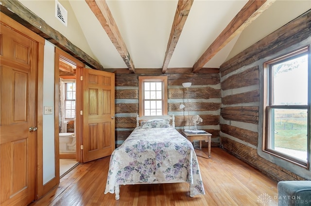 bedroom featuring connected bathroom, vaulted ceiling with beams, multiple windows, and light wood-type flooring