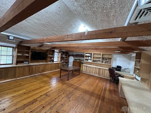 unfurnished living room featuring beam ceiling, a textured ceiling, and wood-type flooring