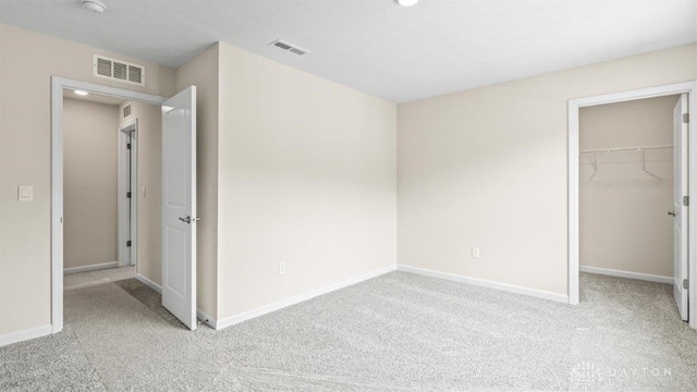 unfurnished bedroom featuring light carpet, a closet, and a spacious closet