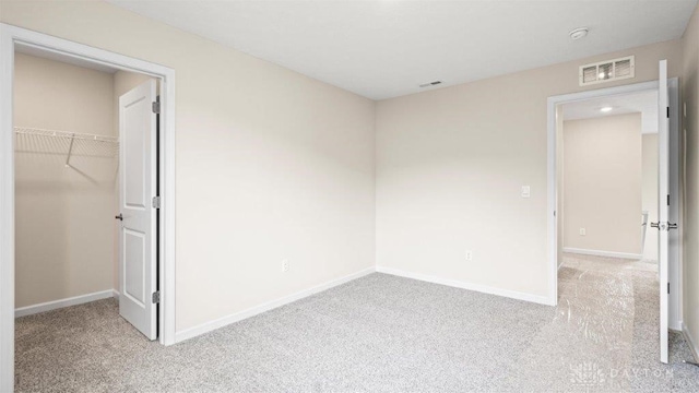 unfurnished bedroom featuring a spacious closet, light carpet, and a closet