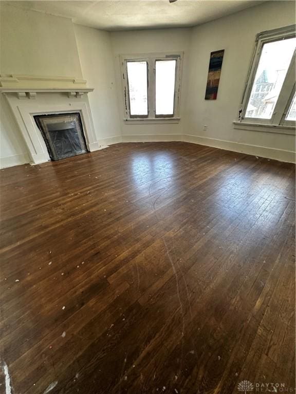 unfurnished living room with a large fireplace, dark hardwood / wood-style floors, and a wealth of natural light